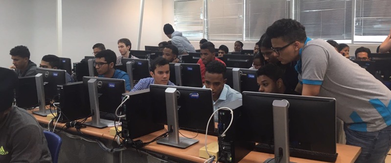 Jovenes en un salon viendo algo en una pantalla de computador