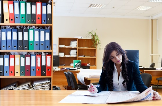 Mujer en un escritorio leyendo un periodico