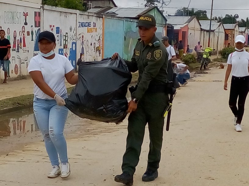 Policia y estudiante llevando una bolsa de basura llena 